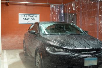 a car in a car wash room with a window covered in water